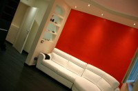 kremowy jasny salon z krwisto czerwoną ścianą za kanapą
