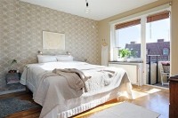 Sypialnia w stylu skandynawskim z piękną tapetą za łóżkiem i równie urokliwą połyskującą w świet ...