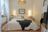 Sypialnia w stylu skandynawskim utrzymana w jasnej tonacji – z charakterystyczną lampą suf ...