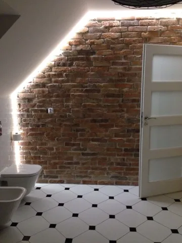 Ściana ze starej cegły z podświetleniem w łazience na poddaszu